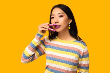 Sarı arka planda rujları olan güzel Asyalı kadın.