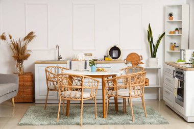 Yeşil bitkilerle, tezgahlarla ve yemek masalarıyla aydınlık mutfağın içinde.