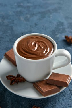 Mavi arka planda lezzetli erimiş çikolatalı bir fincan.