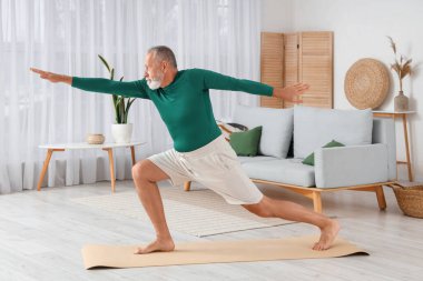 Sportif olgun adam evde yoga yapıyor.