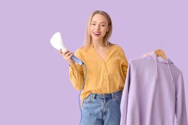 Güzel, genç bir kadın. Leylak arka planında modern buharlı giysiler.