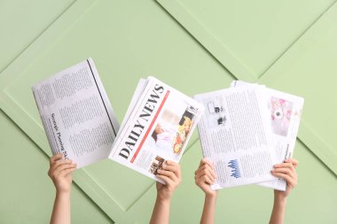 Renk duvarına karşı farklı gazeteleri olan kadın eller, yakın plan.