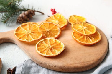 Wooden board with dried orange slices on white background