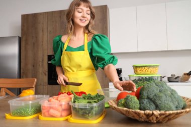Beautiful young woman with different vegetables for freezing in kitchen