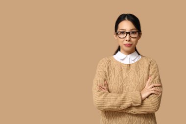 Bej arka planda gözlüklü genç Asyalı iş kadını portresi