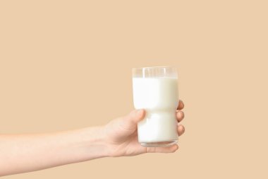 Bej arka planda bir bardak sütle.