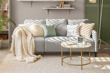 Rahat bir kanepe ve gri duvarın yanındaki masa.