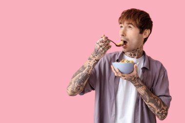 Pembe arka planda mısır gevreği yiyen adam.