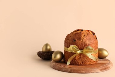 Lezzetli Paskalya pastası ve bej arka planda boyanmış yumurtalarla ahşap tahta.