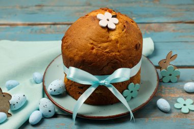 Lezzetli bir Paskalya pastası, mavi ahşap arka planda boyanmış yumurtalar ve tavşanlar.