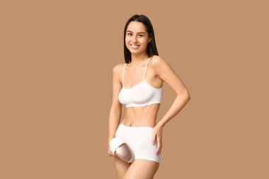 Kahverengi arka planda modern fotoğraf makinesi olan mutlu genç bir kadın.