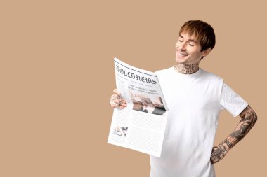Bej arka planda gazetesi olan yakışıklı bir genç.