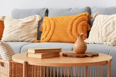 Sehpanın üzerinde kitaplar olan vazo, şık gri kanepenin yanında.