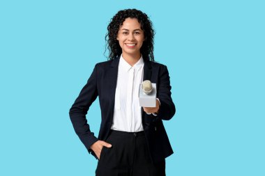 Mavi arka planda mikrofonu olan güzel, genç, mutlu bir Afro-Amerikan kadın gazeteci.