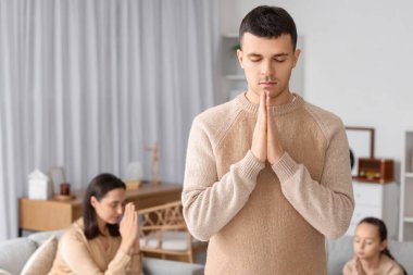 Genç adam evde dua ediyor.