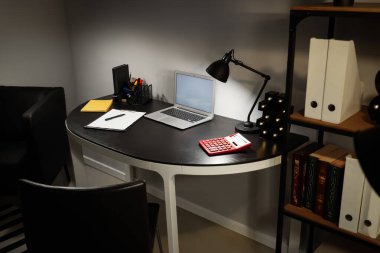 Ofis içi işyeri, boş laptop ve geceleri parlayan lamba.