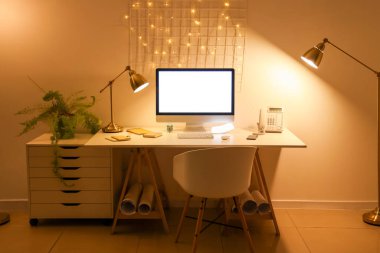 Ofis içi işyeri, boş bilgisayar ve geceleri parlayan lambalar.