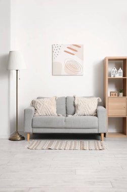 Rahat kanepesi, lambası, resmi ve rafları olan modern oturma odası.