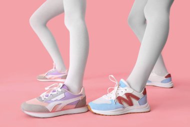 Beyaz taytlı kadın bacakları pembe arka planda şık ayakkabılar giyiyor.