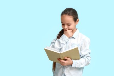 Mavi arka plan üzerine kitap okuyan küçük kız.