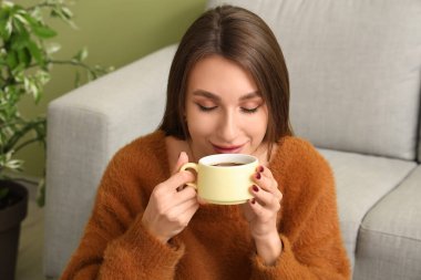 Evde bir fincan çayla genç bir kadın, yakın plan.