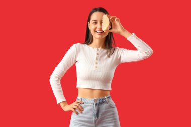 Smiling young woman with pomelo slice on red background clipart