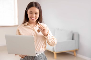 Dairede dizüstü bilgisayarı ve anahtarı olan Asyalı emlakçı