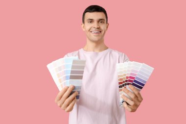 Pembe arka planda boya paletleri olan genç bir adam.