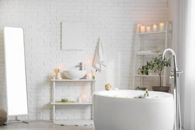 İçinde yanan mumlar, küvet ve lavabo olan hafif bir banyo.