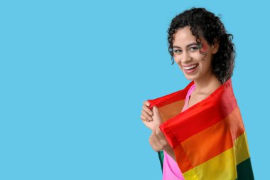 Mavi arka planda gökkuşağı bayrağı olan genç bir Afro-Amerikalı kadın. LGBT kavramı