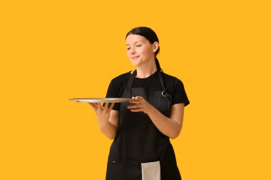 Sarı arka planda tepsisi olan güzel bir garson kız.