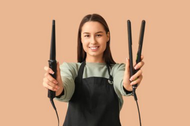 Saç maşasıyla kadın kuaför ve kahverengi arka planda düzleştirici.