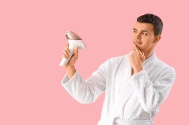 Pembe arka planda fotokopi makinesi olan düşünceli bir genç adam.