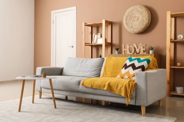 Gri kanepesi, masası ve raf ünitesi olan şık bir oturma odası.