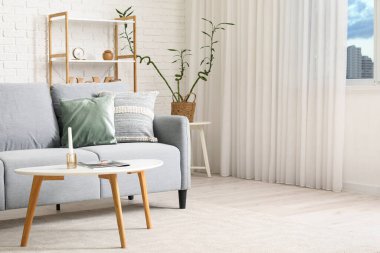 Gri kanepesi, masası ve raf ünitesi olan modern oturma odası.