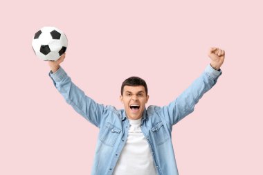 Pembe arka planda futbol topu olan duygusal genç bir adam.