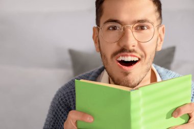 Yatak odasında kitap okuyan mutlu genç adam, yakın çekim.