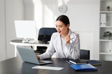 Masada dizüstü bilgisayarla çalışan genç Asyalı iş kadını.