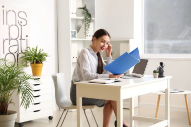 Ofiste çalışan dosyasıyla genç Asyalı iş kadını.