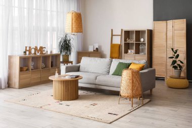 Gri kanepesi, ahşap masası ve lambaları olan rahat bir oturma odası.