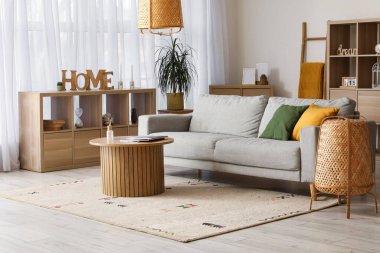 Gri kanepesi, ahşap masası ve lambaları olan rahat bir oturma odası.