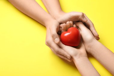 Sarı arka planda kırmızı kalpli kadın ve çocuğun elleri