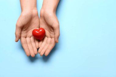 Mavi arka planda kırmızı kalpli kadın elleri