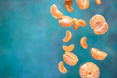 Mavi arka planda soyulmuş tatlı mandalinalar uçuyor