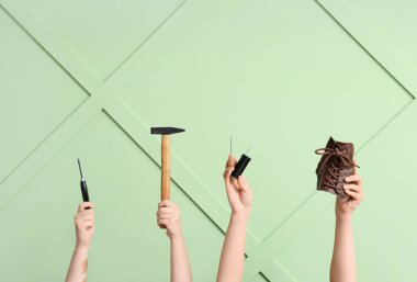 Ayakkabı parçalı kadın eller ve yeşil ahşap arka planda el aletleri. Ayakkabı tamir konsepti