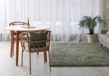 Masası, koltukları ve çiçekleri olan rahat, ferah bir oturma odası.