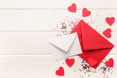 Kalpli zarflar ve beyaz ahşap arka planda konfeti. Sevgililer Günü kutlaması