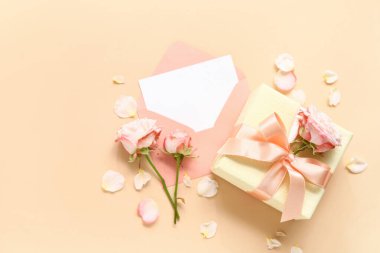İçinde boş kart, hediye kutusu ve bej arka planda güller olan zarf.