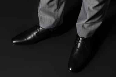 Siyah arka planda zarif ayakkabılı genç adam bacakları.