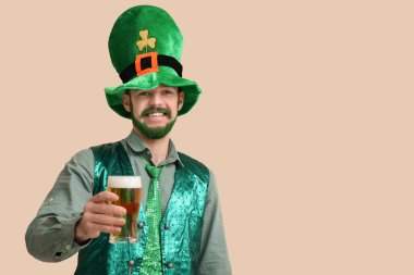 Yeşil sakallı, yeşil sakallı, bej arka planda bir bardak bira tutan mutlu genç adam. Aziz Patrick Günü kutlaması